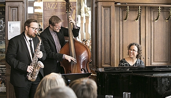 Die Jazz-Hits werden von einem Jazz-Trio mit Saxophon, Klavier und Kontrabass interpretiert.