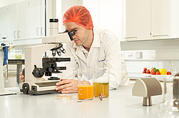 Ein Mitarbeiter beim Mikroskop untersucht eine Flüssigkeit