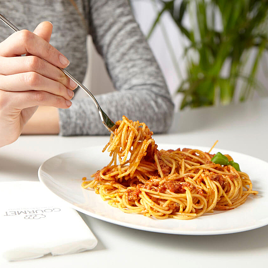 GOURMET Essen am Arbeitsplatz: Person isst Spaghetti Bolognese