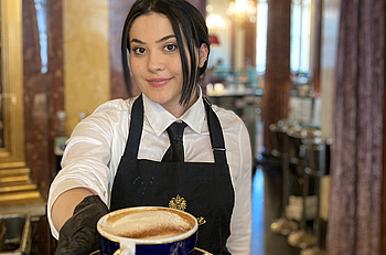 Mitarbeiterin von Kaffeehaus serviert Kaffee